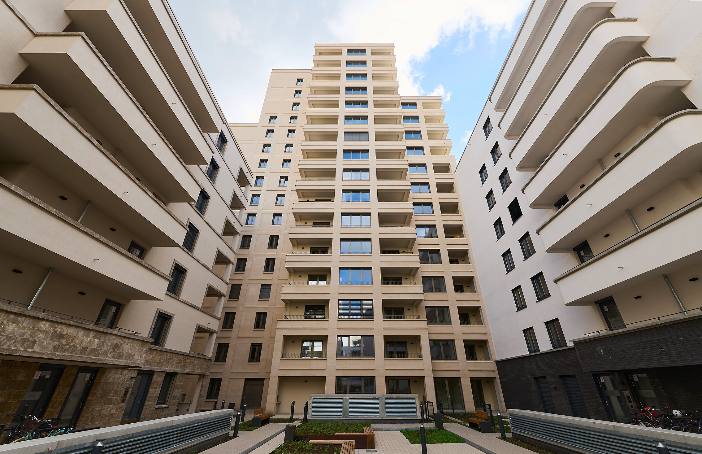 Zu sehen ist das Projekt DREI HORIZONTE vom Innenhof aus auf das Gebäude mit Sitzmöglichkeiten