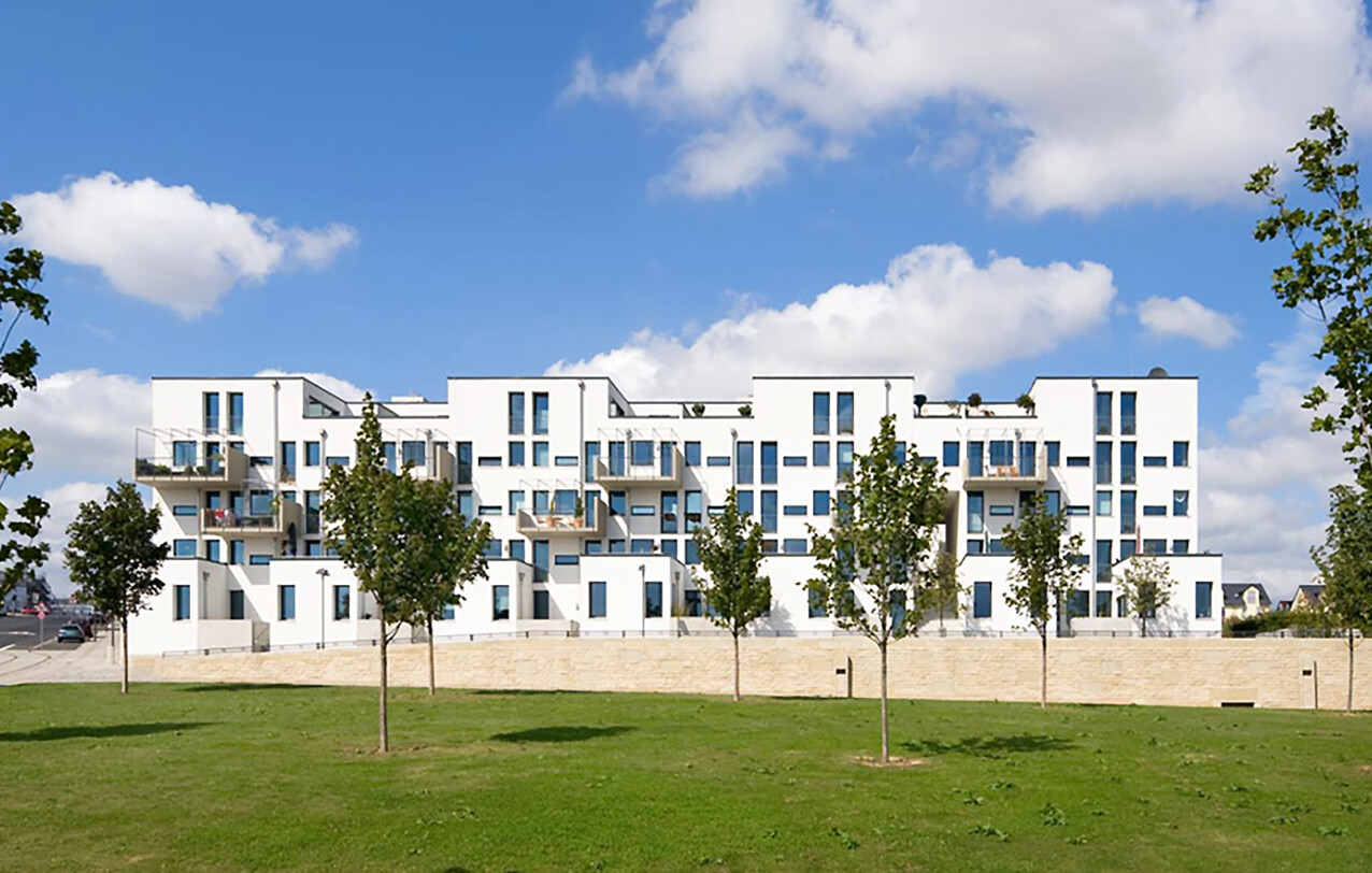 Mit Blick aus der Ferne und von der Straße aus auf die Frontansicht eines Hauses des BUWOG Neubauprojekts Take5 im Rhein-Main-Gebiet