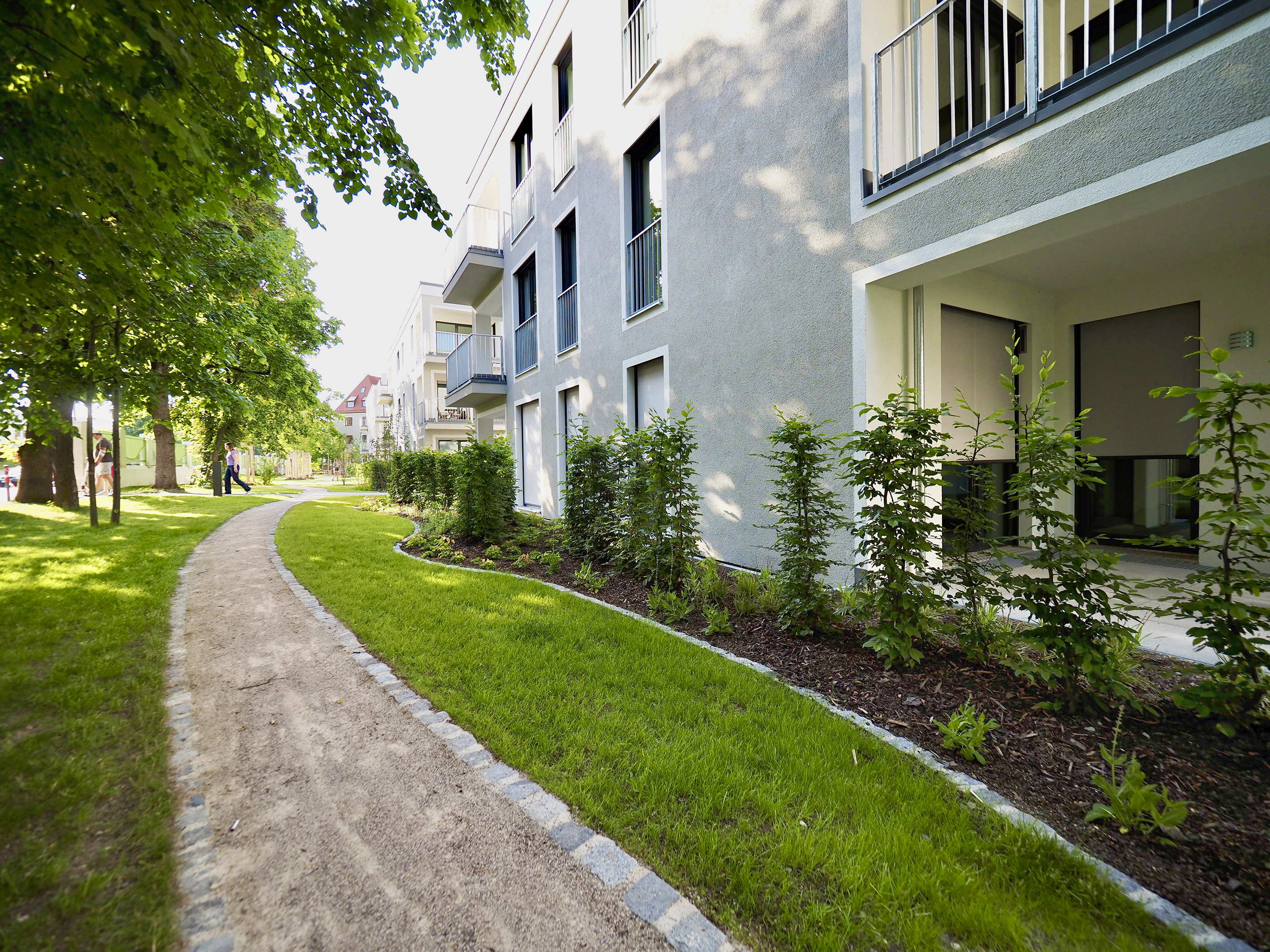 The green area of the quarter with pedestrian path and plantings can be seen.